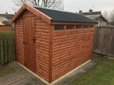 Warm stained apex garden shed with single door and high-level windows on patio