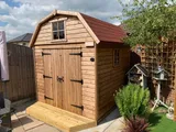 Dutch Barn shed with shingle roof, double doors and high-level gable window on sunny patio