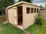 Pent roof garden shed with door open and row of four side windows