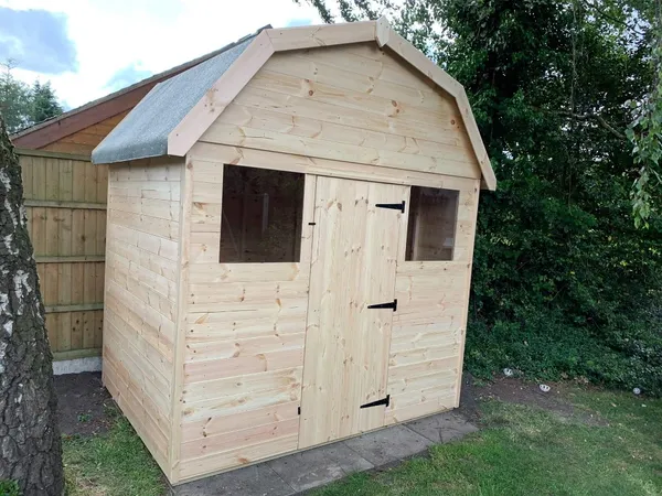 Dutch Barn shed with gambrel roof, single door and two front windows, natural timber on paving