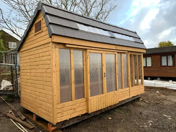Natural timber apex stock loft with tiled roof, roof lights, and large sliding polycarbonate windows revealing internal wire mesh