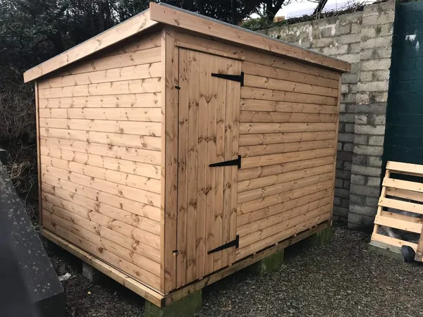 Natural timber pent shed with single door and strap hinges on raised base