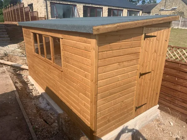 Pent roof timber shed with row of four windows and single door