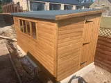 Pent roof timber shed with row of four windows and single door