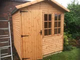 Classic apex timber garden shed with single door and two multi-pane windows in a garden setting