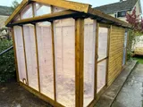 Large timber potting shed on brick dwarf wall with expansive angled roof glazing