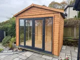Front view of the natural timber Modern Apex summerhouse installed on a patio base