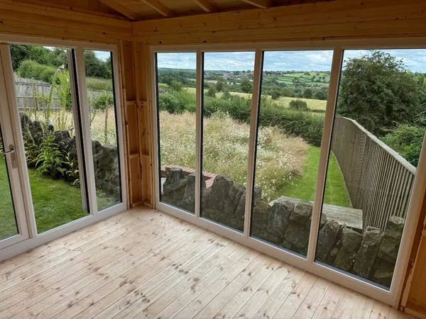Modern Apex summerhouse with anthracite French doors and sidelights on a flagstone patio with timber base
