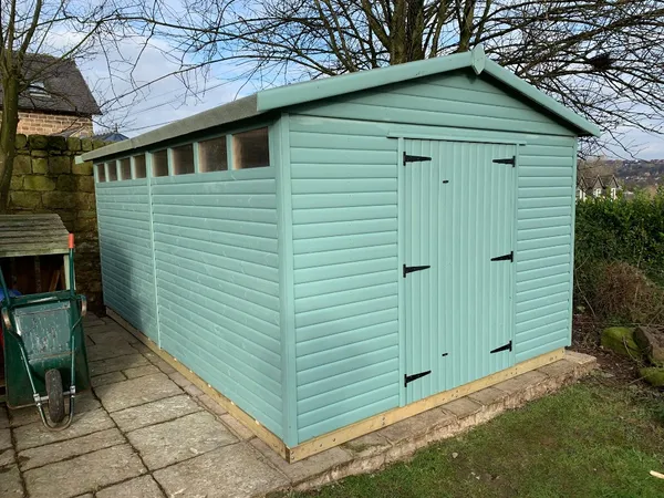 Apex timber workshop with four windows, single door and wide double doors open, tools visible inside