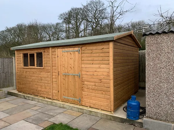Mint green apex timber workshop with double doors, central multi-pane window and single side door in a garden