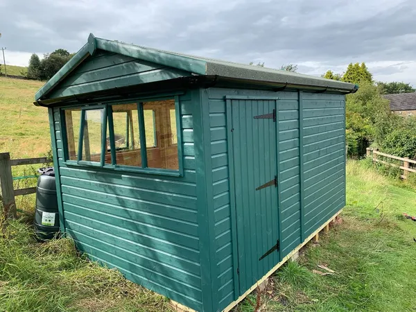 Natural wood apex workshop with two pairs of double doors and central window in garden