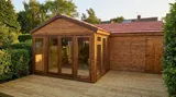 Warm evening light on a natural wood corner summerhouse sitting on a timber deck