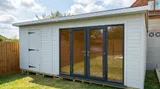 The Denby Combi Summerhouse with glazed garden room and solid storage door in a sunny garden