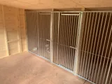 Interior of professional dog kennel showing galvanised steel bar panels and secure gates