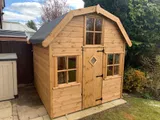 Dutch Barn shed with felt shingle roof and side-opening windows, timber cladding