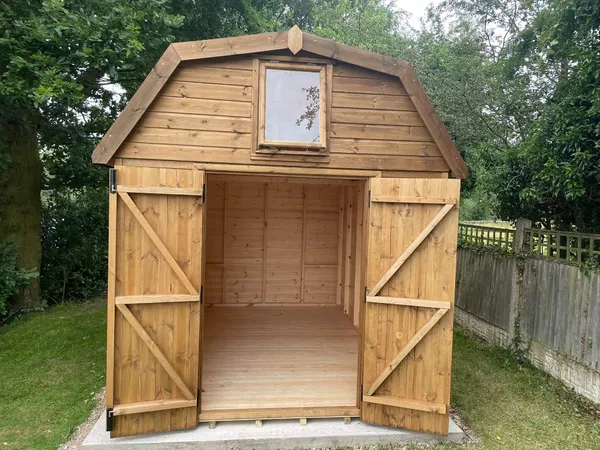 Dutch Barn shed with diamond window in door and four-pane side windows, natural timber