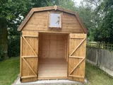 Dutch Barn shed with diamond window in door and four-pane side windows, natural timber