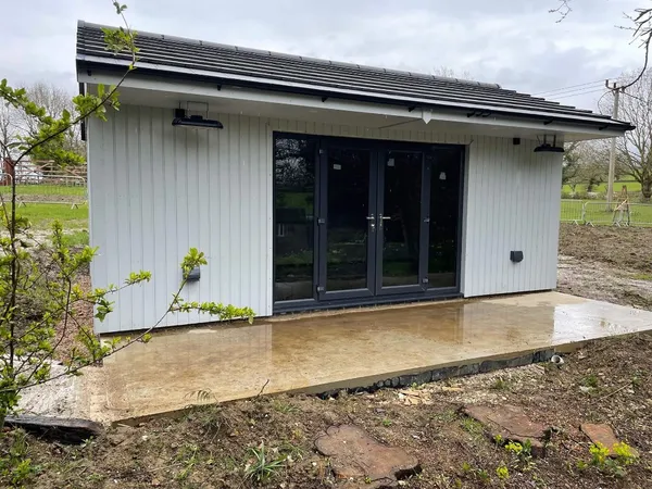 The Executive Apex Garden Studio with white vertical cladding, integrated downlights and concrete patio