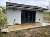 The Executive Apex Garden Studio with white vertical cladding, integrated downlights and concrete patio