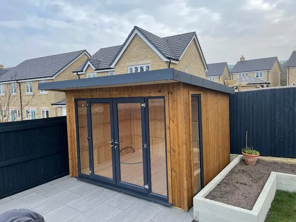 The Modern Pent Garden Room with vertical timber cladding, anthracite grey French doors and full-height corner window on patio