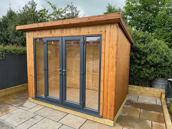 The Modern Pent Garden Room with vertical timber cladding and full-height French doors on paved patio
