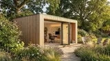 The Pentrich Garden Room with vertical slatted cedar cladding, bi-fold doors and recessed canopy lighting, set up as a luxury home office in a landscaped garden