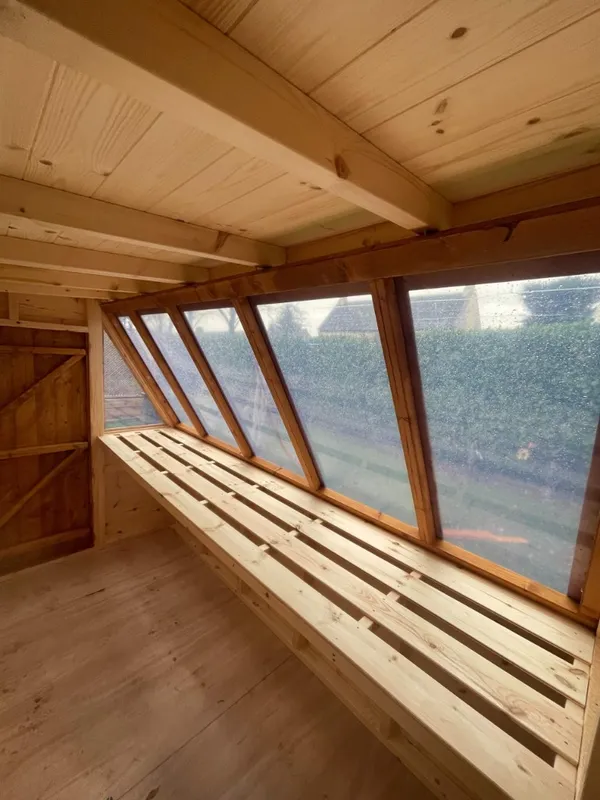 Dual-purpose timber potting shed with glazed greenhouse section and solid storage area, both doors open on a prepared base