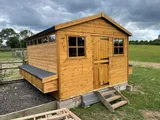 Walk-in professional poultry shed in pasture with external nest boxes and full-height door