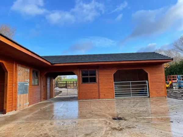 L-shaped timber stable block and courtyard with half-doors, archway and open bay, wet paved yard