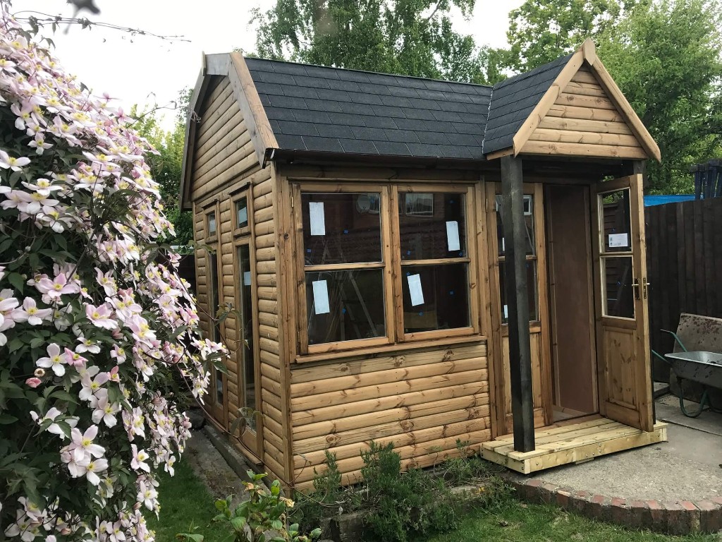 Finished bespoke timber shed built by Ecco – natural loglap cladding, dark shingled roof, gabled porch and multiple windows, UK built